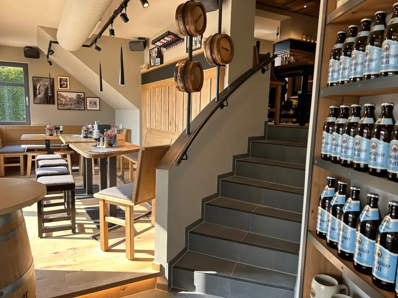 Treppe mit Bierfässern an der Wand und Regal voller Benediktiner Flaschen